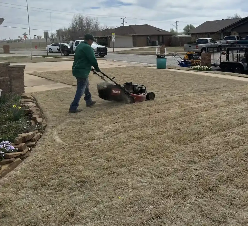 Technician mowing dormant lawn during early season lawn care