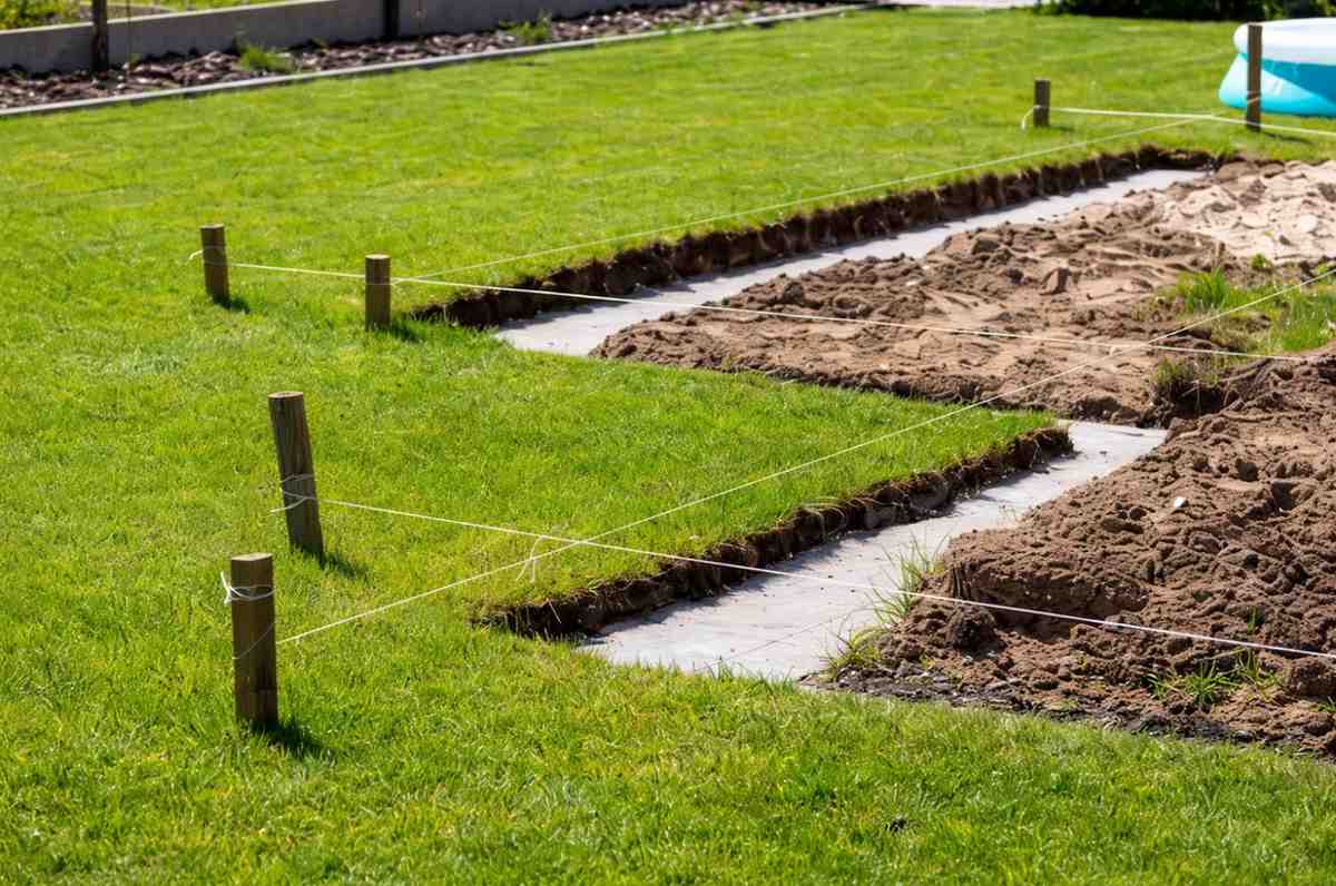 Lawn treatment process with trenches marked using stakes and string for lawn care and soil preparation